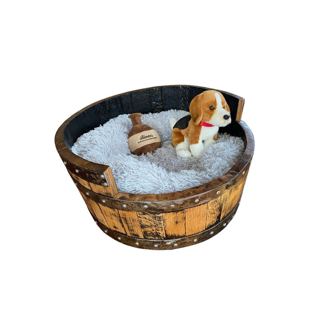 A plush dog toy rests in the premium Dog Bed Wooden, featuring a handmade solid wood barrel construction and a fluffy cushion.